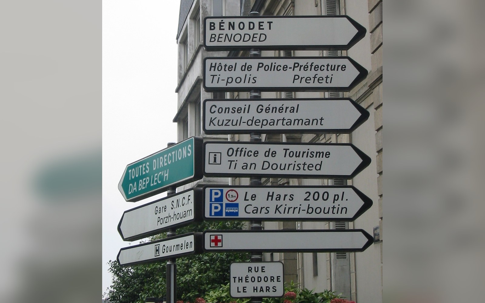 Bilingual French and Breton street signs pointing toward local landmarks and offices in Quimper